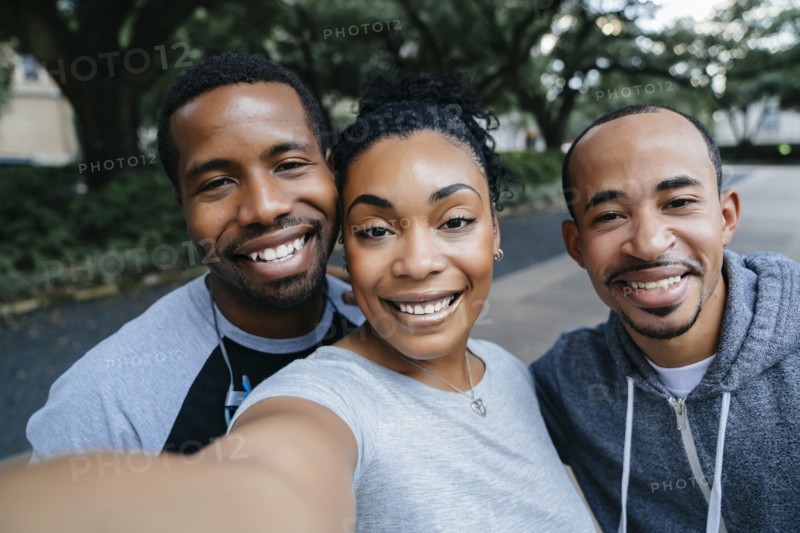 Smiling Black friends posing for cell phone selfie