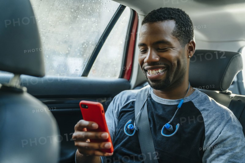 Smiling Black man texting on cell phone in car