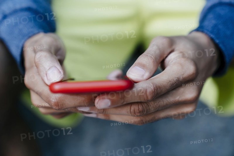 Hands of Black man texting on cell phone