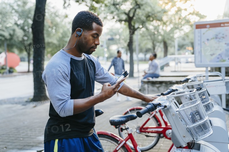 Black man paying for bicycle rental with cell phone