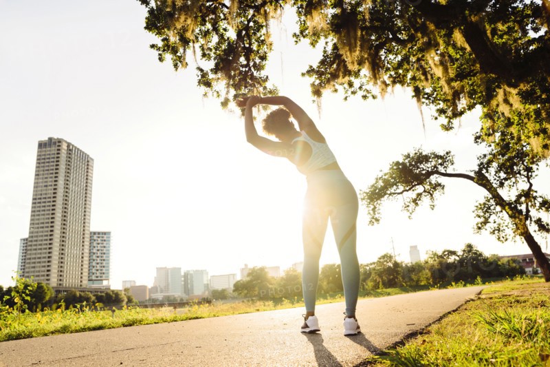 Mixed Race woman stretching on running path in park