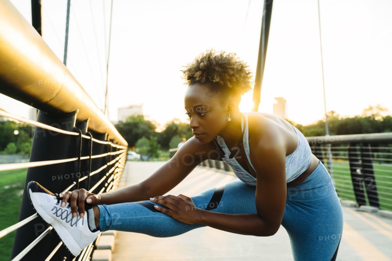 Mixed race woman stretching leg on bridge railing