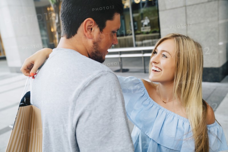 Caucasian couple hugging and carrying shopping bags