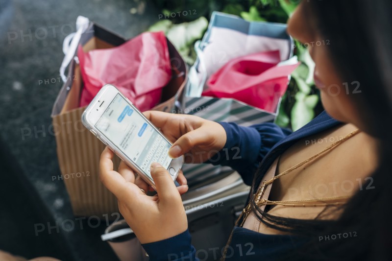 Hispanic woman with shopping bags texting on cell phone