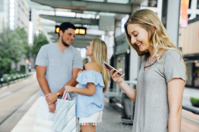 Caucasian woman at train station texting on cell phone