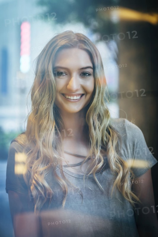 Portrait of smiling Caucasian woman behind window
