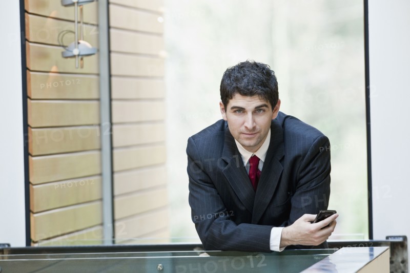 Mixed race businessman leaning on office railing