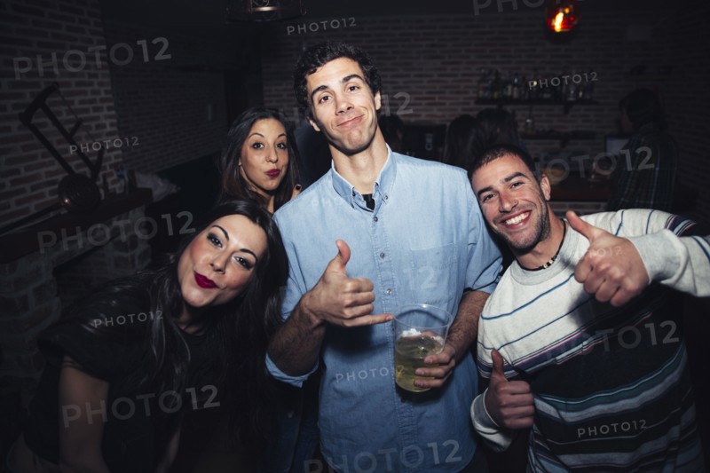 Laughing friends giving thumbs up in nightclub