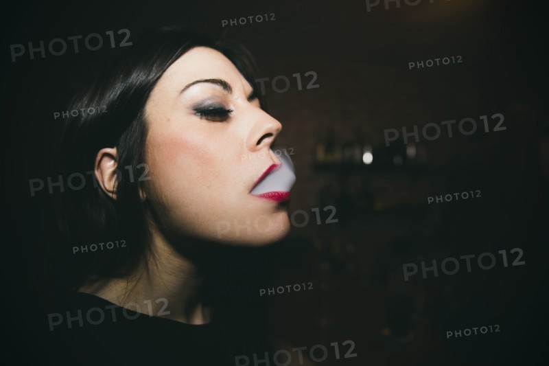 Caucasian woman smoking in nightclub