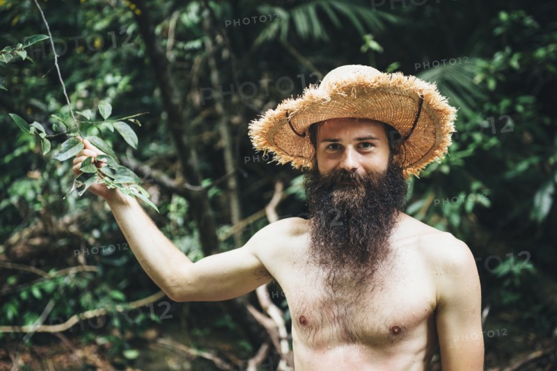 Caucasian man with bare chest holding branch in forest