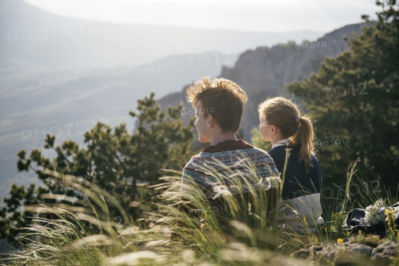 Caucasian couple sitting on hill admiring scenic view