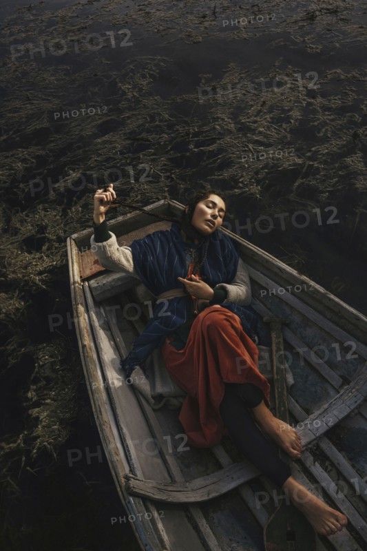 Location woman wearing traditional clothing laying in rowboat
