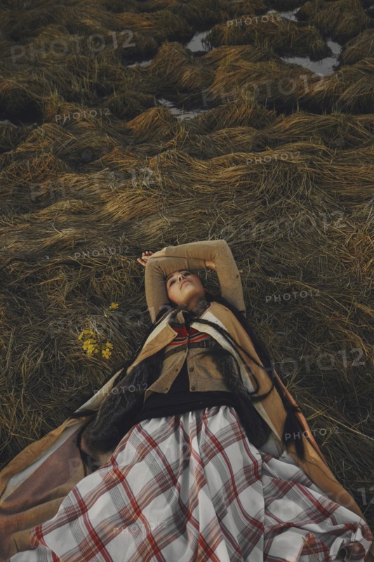 Caucasian woman wearing traditional clothing laying in grass