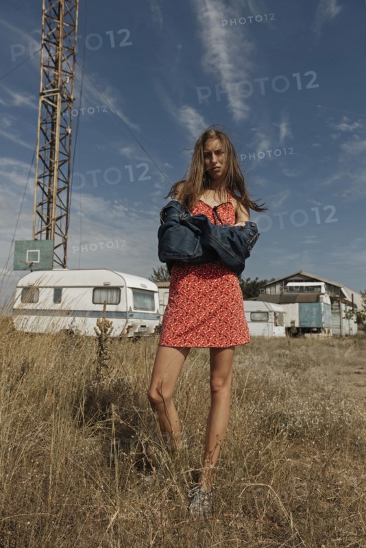 Serious Caucasian woman standing in field near trailers
