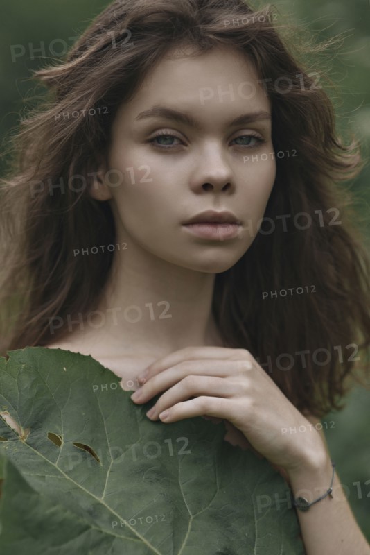 Caucasian woman covering chest with leaf