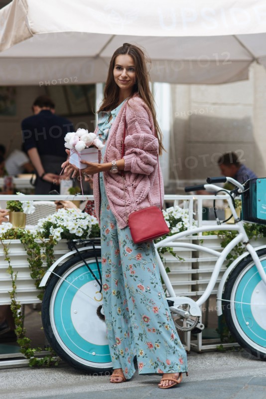 Caucasian woman carrying gift box near bicycle