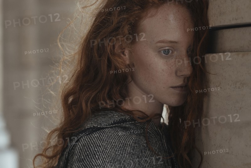Serious Caucasian woman leaning face on pillar