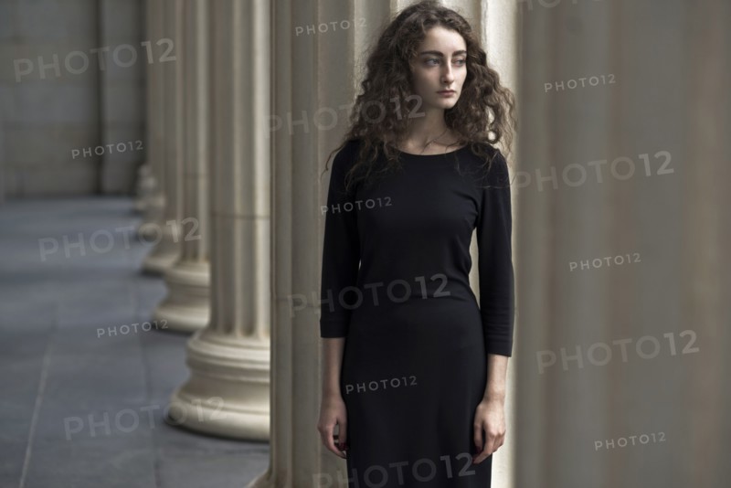 Serious Caucasian woman standing near pillars