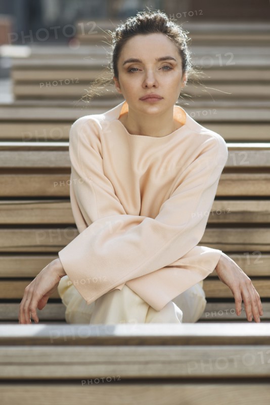 Portrait of serious Caucasian woman sitting on wooden bench