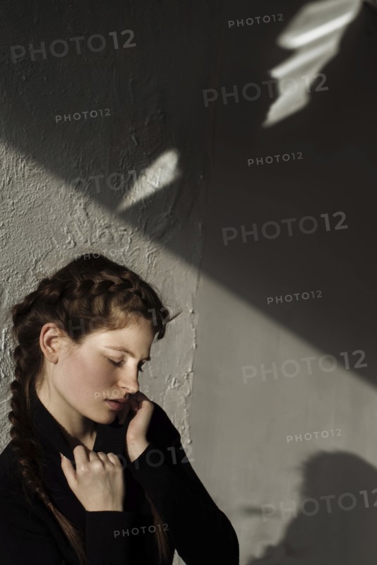 Shadow on wall over pensive Caucasian woman