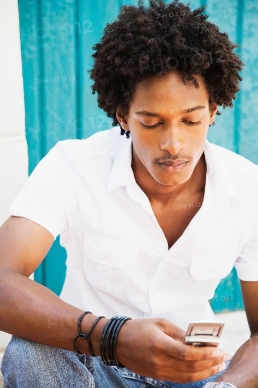 African man looking down at cell phone