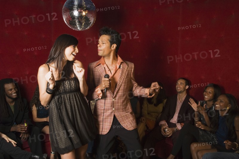 Man and woman singing karaoke at nightclub