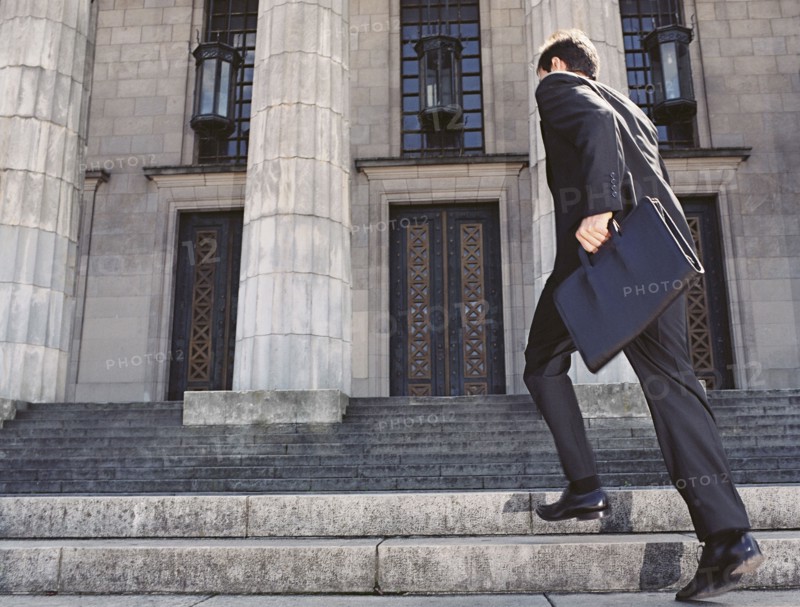 Businessman running up stone stairs