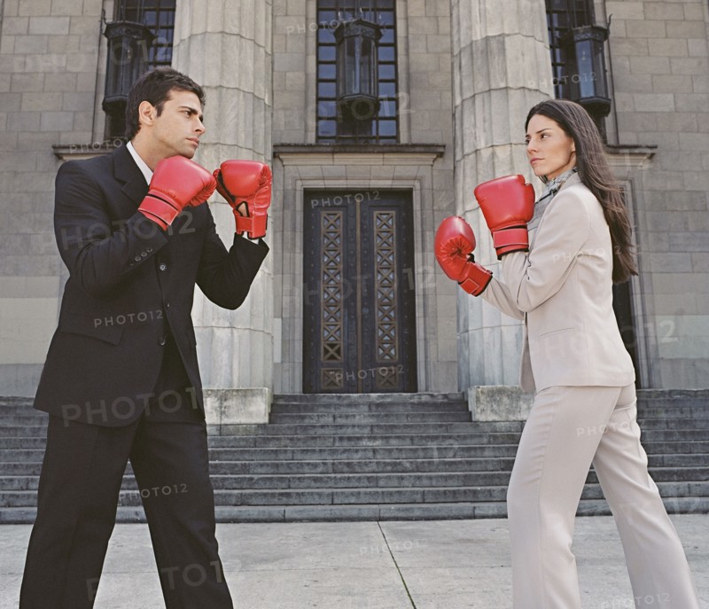 Businessman and businesswoman sparring in front of building