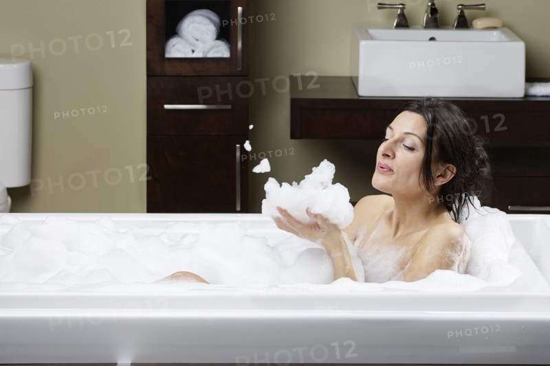 Caucasian woman blowing bubbles in bubble bath