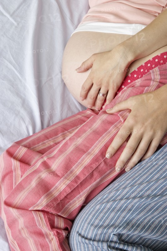 Caucasian lesbian couple holding pregnant belly