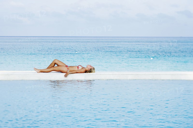Caucasian woman laying by infinity pool