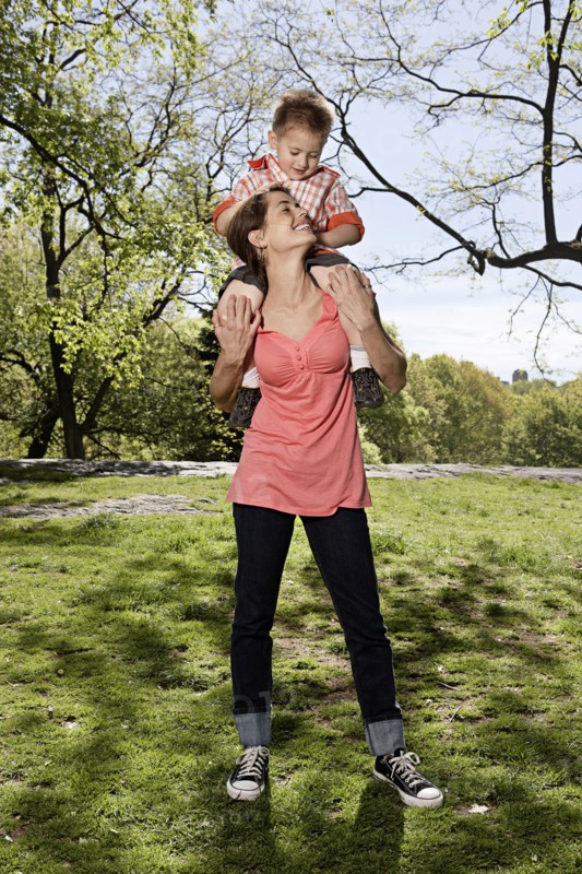 Mixed race woman carrying son on shoulders in park