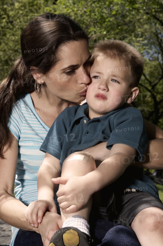 Mixed race mother kissing hurt son in park