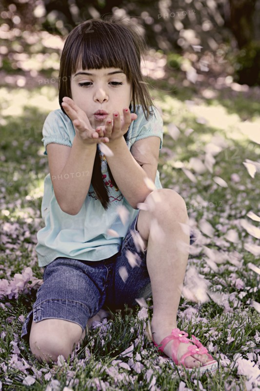 Mixed race girl playing with flowers in park