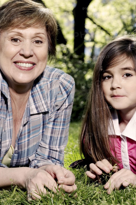 Senior Caucasian woman and granddaughter laying in grass