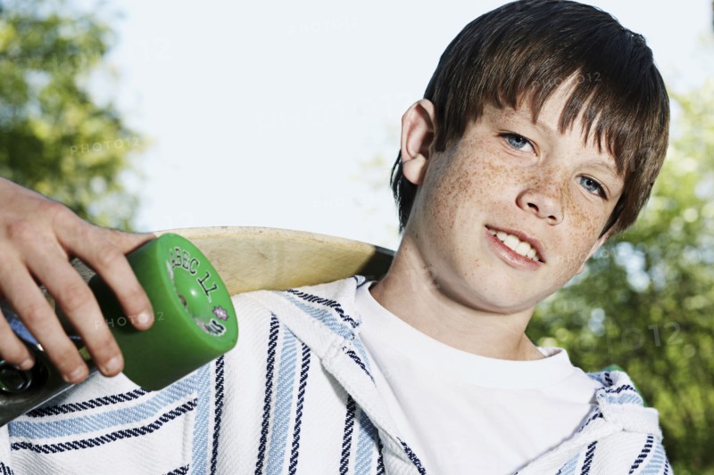 Caucasian boy holding skateboard outdoors