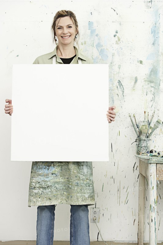 Caucasian painter holding blank canvas in studio