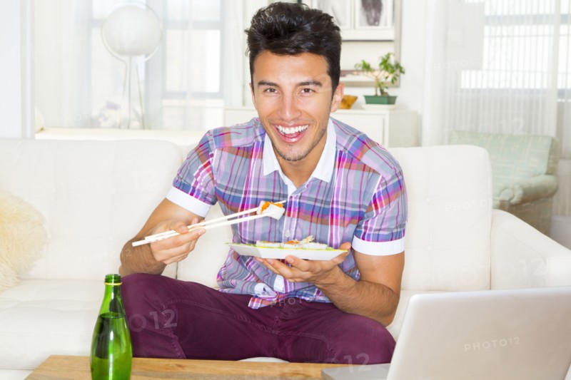 Mixed race teenager eating sushi on sofa