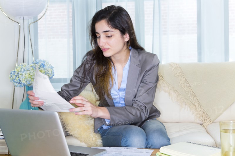Hispanic woman using laptop on sofa