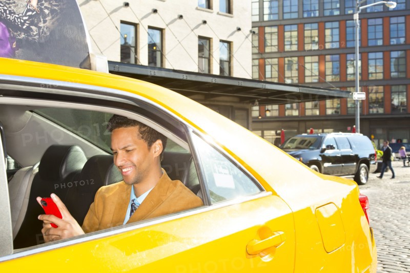 Mixed race businessman using cell phone in taxi