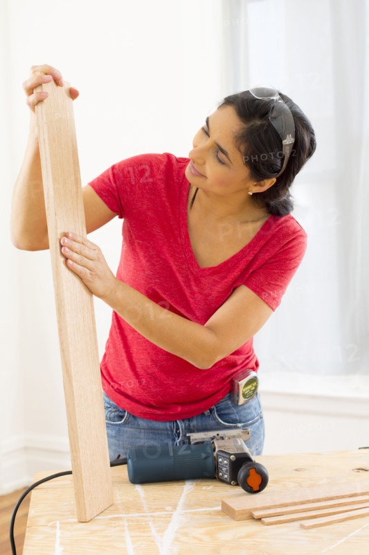 Mixed race woman examining plank of wood