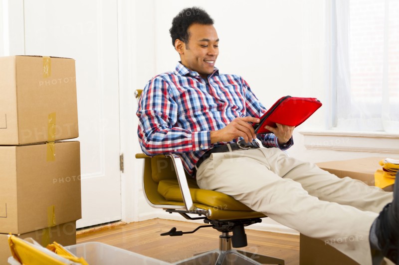 Mixed race man using digital tablet in new home