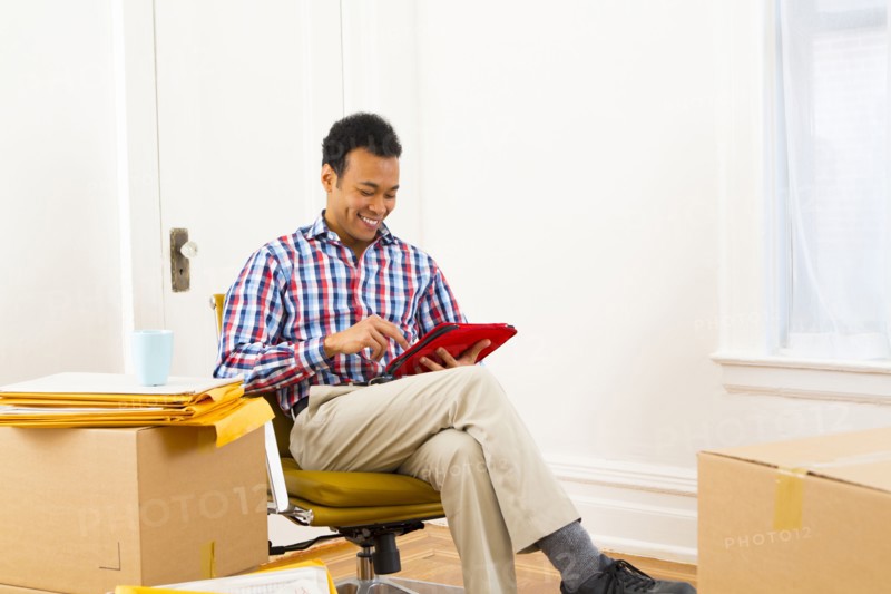 Mixed race man using digital tablet in new home