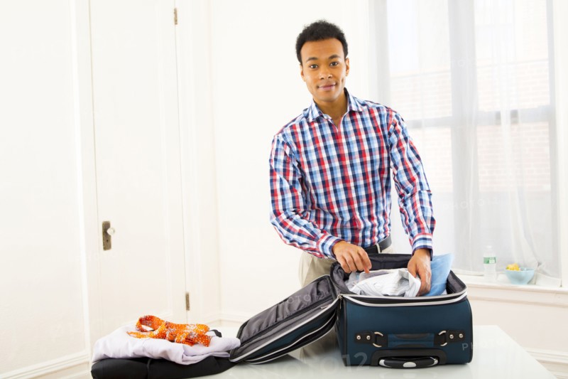 Mixed race businessman packing suitcase