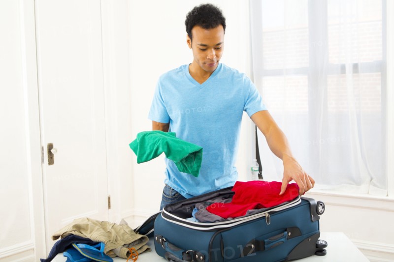 Mixed race man packing suitcase
