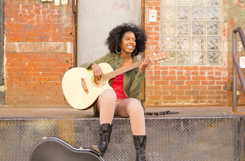 Mixed race woman playing guitar in city