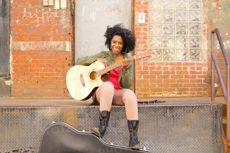 Mixed race woman playing guitar in city