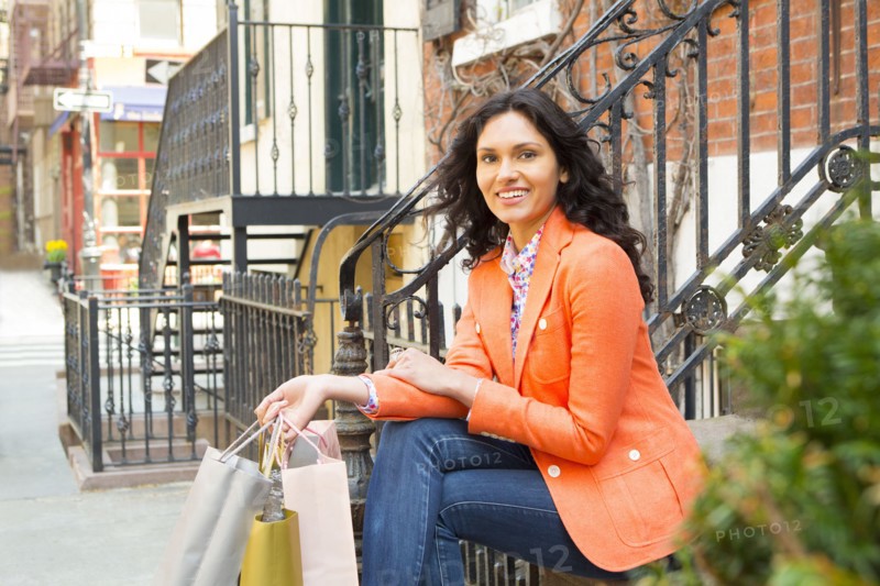Mixed race woman with shopping bags on city sidewalk