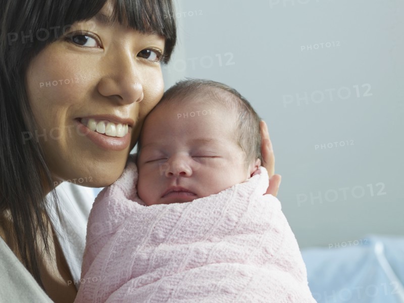 Mixed race mother cuddling newborn baby