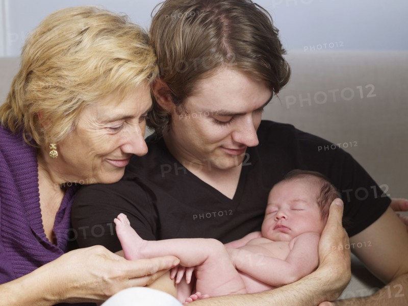 Senior mother and son cuddling newborn baby